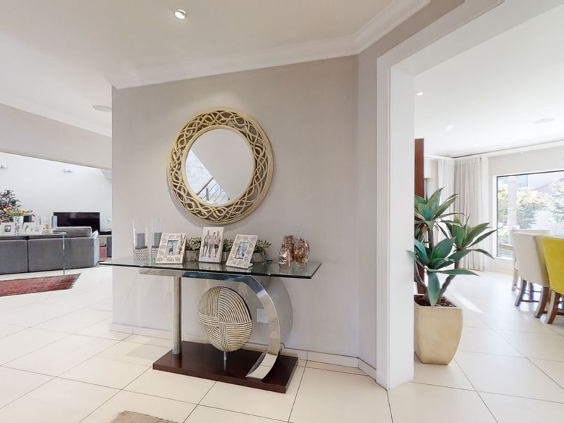 A bright and welcoming entrance hall featuring neutral tiled flooring, coved ceiling cornices, and recessed lighting, providing a seamless transition into the open-plan living areas.