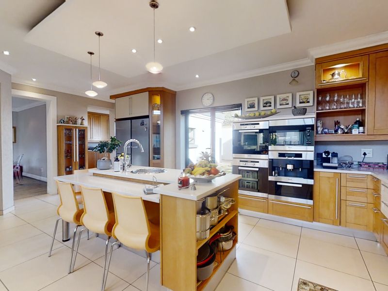 A well-appointed kitchen featuring a central island, built-in appliances, ample cabinetry, and modern recessed lighting with a functional layout.