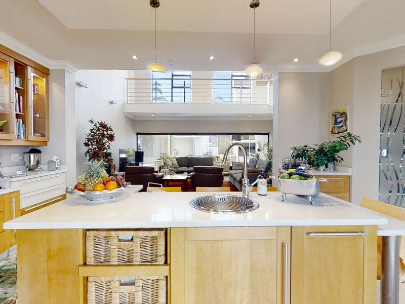 Spacious open-plan kitchen featuring a central island with sink, wooden cabinetry, and a mezzanine level overlooking the living area.