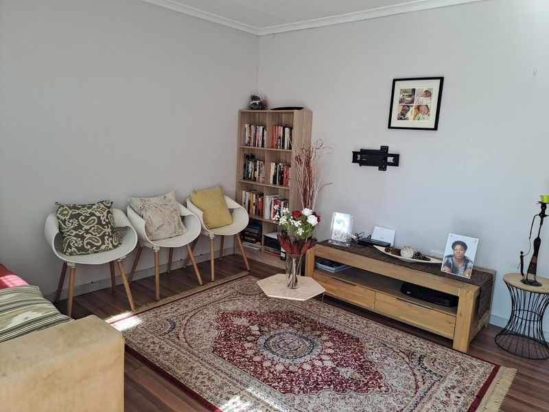 A comfortable living room featuring laminate flooring and a wall-mounted television bracket, providing a functional space for relaxation.