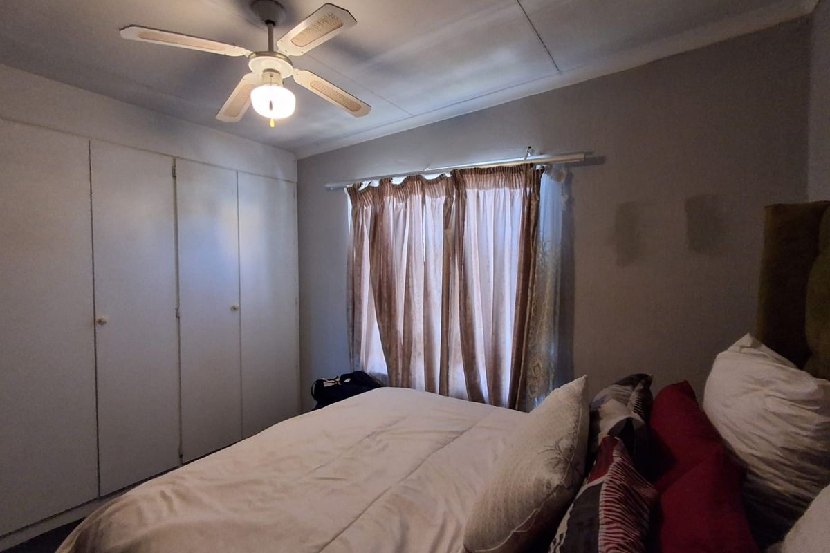 A bedroom featuring built-in cupboards and a ceiling fan, providing functional storage and climate control.
