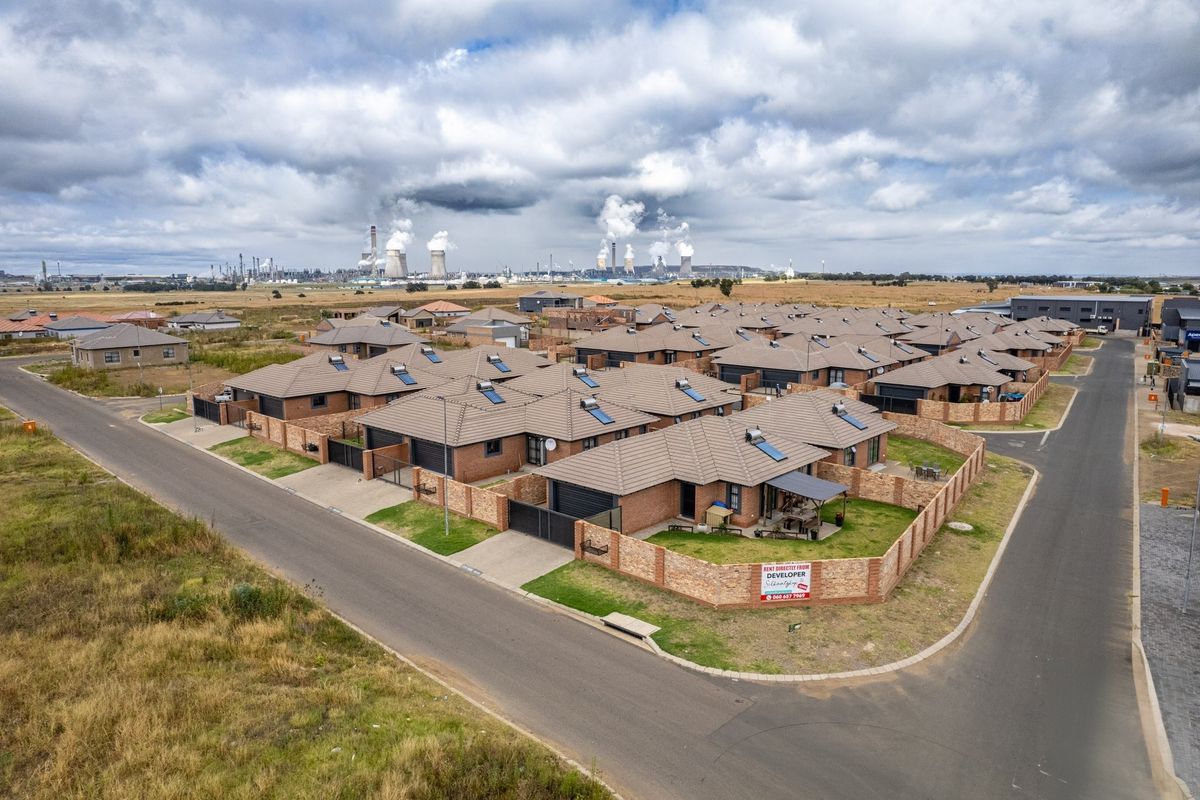 Aerial view of a modern residential estate featuring brick homes with tiled roofs, solar water heaters, and private boundary walls.