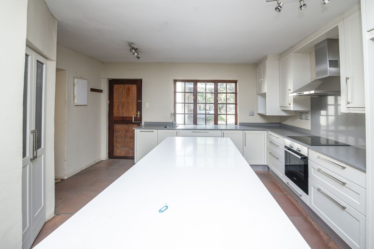 Spacious kitchen featuring a large central island, modern built-in cabinetry, integrated oven and hob, and a functional layout with direct exterior access.