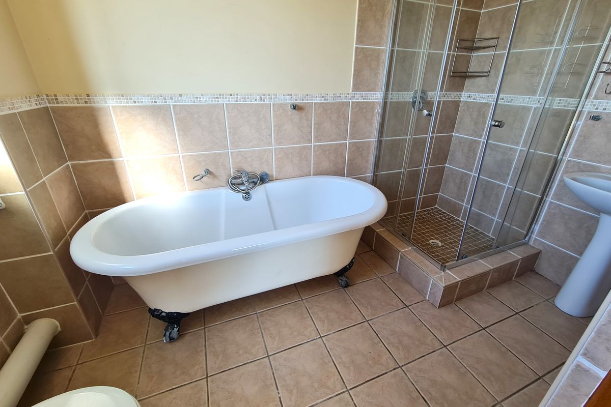 Bathroom featuring a classic freestanding bathtub, a separate glass-enclosed shower, and a pedestal basin with neutral wall and floor tiling.