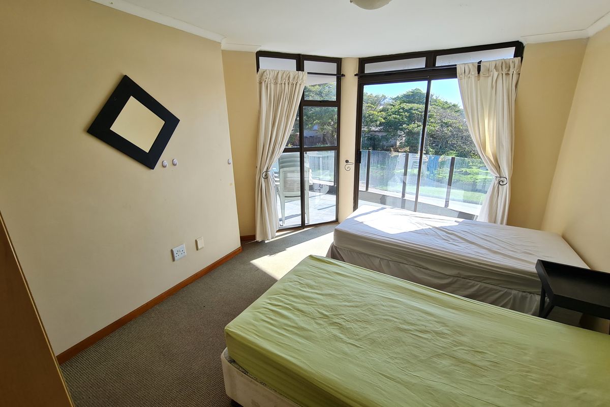 A bedroom featuring carpeted flooring and large sliding glass doors that provide access to an outdoor balcony area.