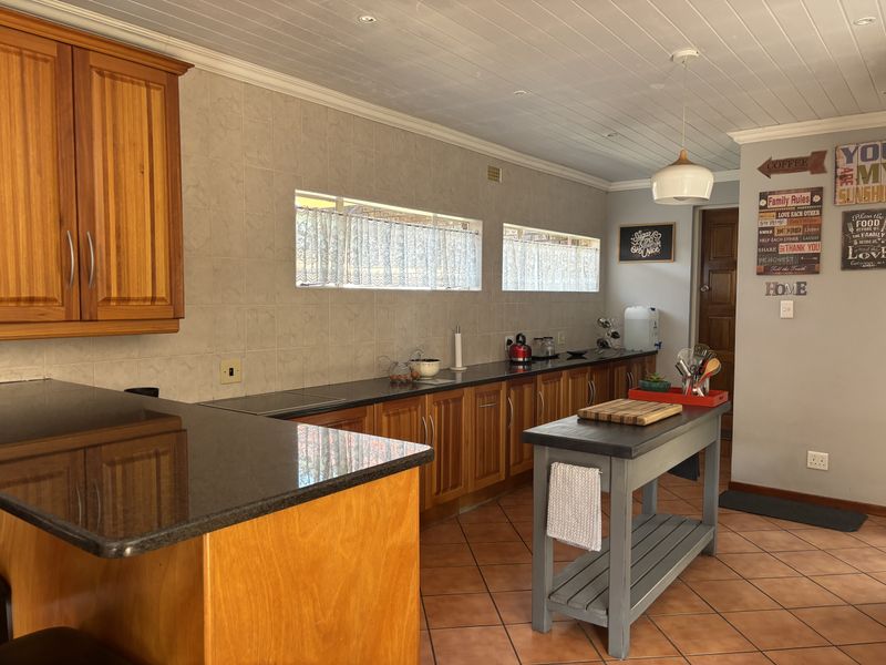 A functional kitchen featuring wooden cabinetry, granite countertops, tiled backsplash, and tiled flooring, complemented by a tongue and groove ceiling.