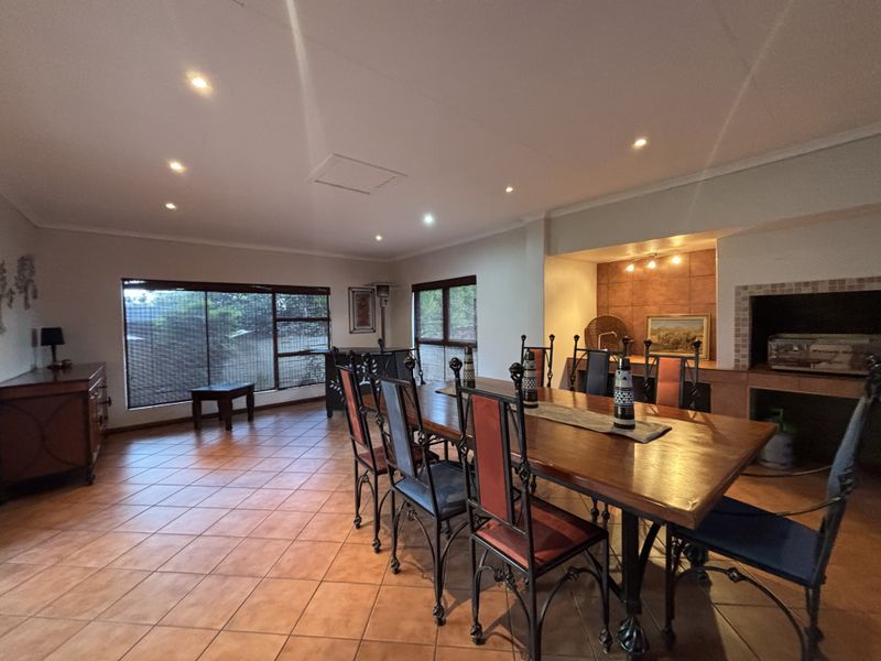 Spacious dining area featuring terracotta floor tiles, recessed lighting, and a built-in indoor braai with a tiled splashback.