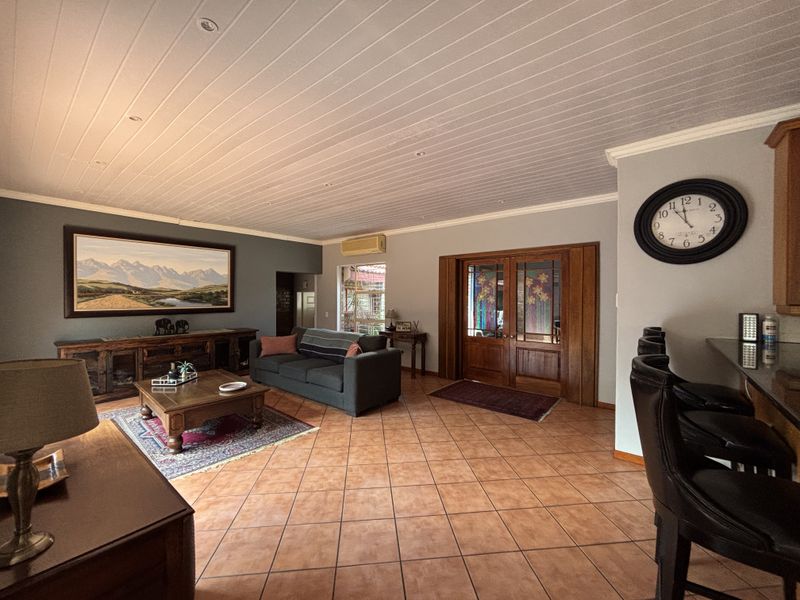 Spacious open-plan living area featuring tiled flooring, a timber panelled ceiling, and a breakfast bar, providing a versatile and comfortable family space.