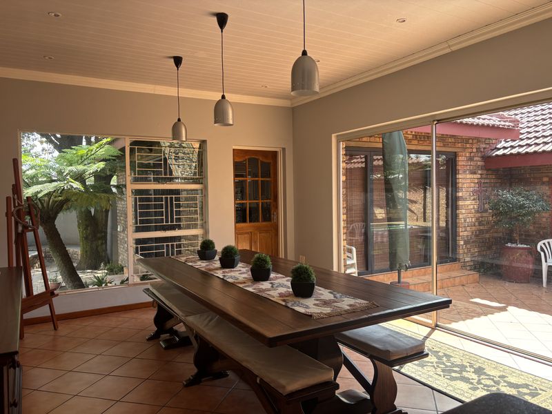 A bright dining area featuring tiled floors, pendant lighting, and large sliding glass doors that provide seamless access to the outdoor patio and garden.