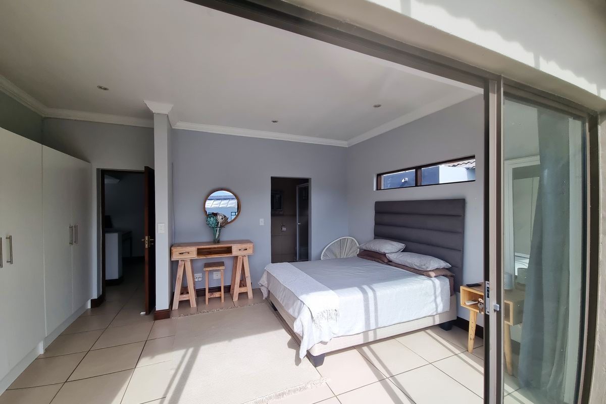 Spacious bedroom featuring tiled flooring, built-in cupboards, and large sliding glass doors that provide ample natural light and access to the outdoors.
