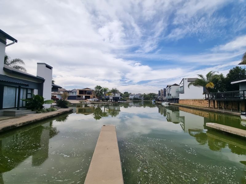 A scenic view of the estate waterway featuring a concrete jetty and surrounding residential properties along the canal banks.