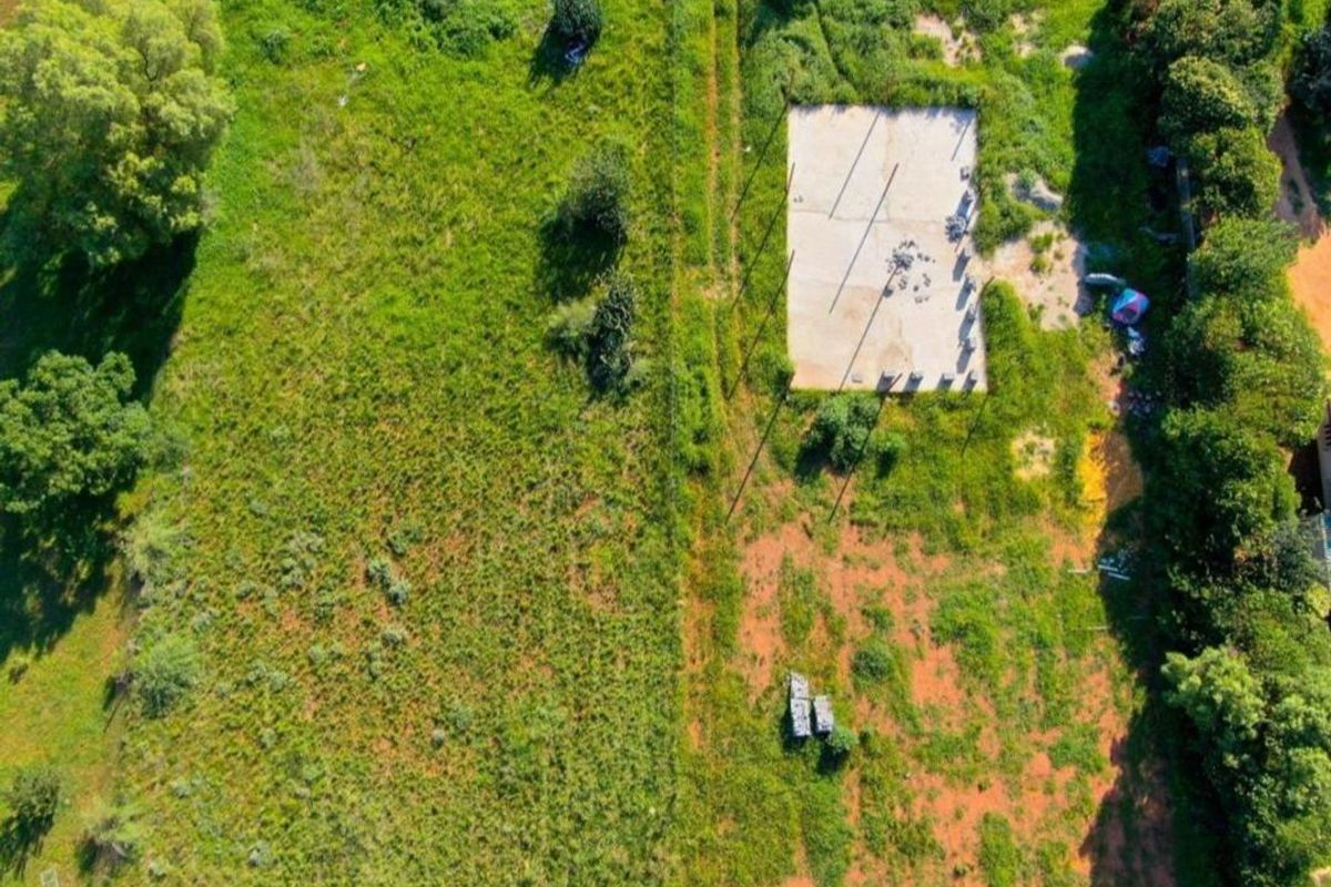 Aerial view of a vacant residential plot featuring an existing concrete slab foundation and surrounding overgrown vegetation.