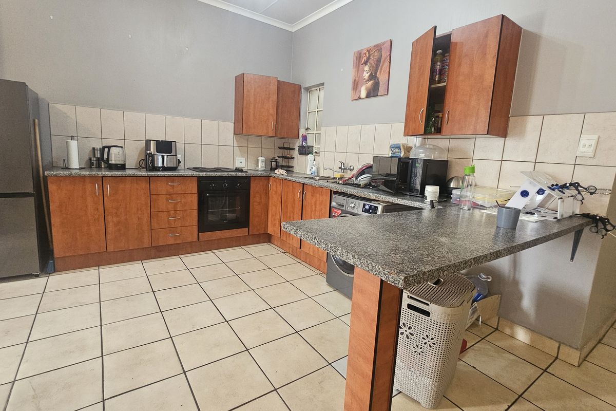 Functional kitchen featuring wood-finish cabinetry, granite-look countertops, tiled backsplash, and integrated oven with hob, offering a practical layout for daily meal preparation.
