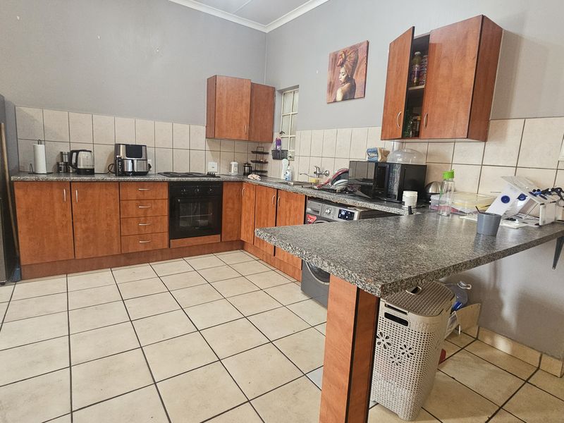 Functional kitchen featuring wood-finish cabinetry, granite-look countertops, tiled backsplash, and integrated oven with hob, offering a practical layout for daily meal preparation.
