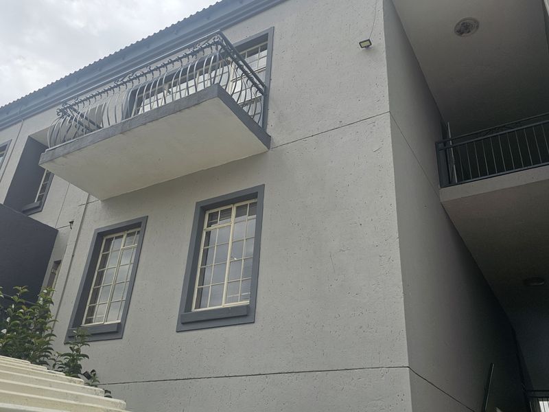 Exterior view of a multi-story apartment building featuring balconies with metal railings and standard window frames.