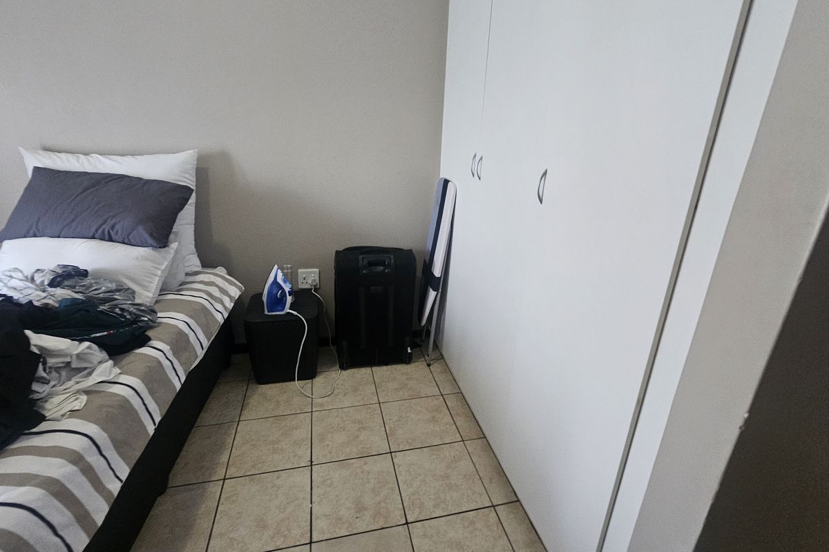 A bedroom featuring built-in cupboards and tiled flooring.