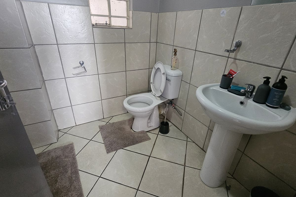 A functional bathroom featuring a pedestal basin, a standard toilet, and full-height wall tiling.