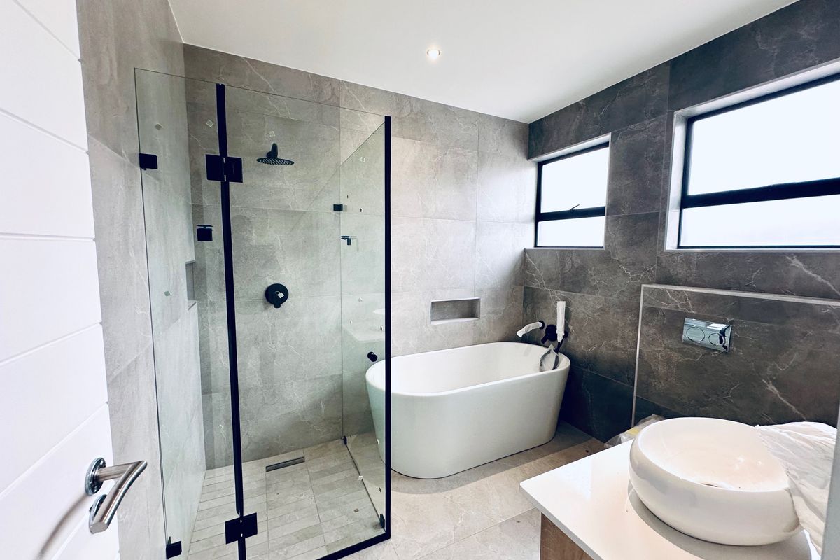 Modern bathroom featuring a sleek freestanding bathtub, a spacious walk-in shower with black fixtures, and a contemporary vessel sink vanity.