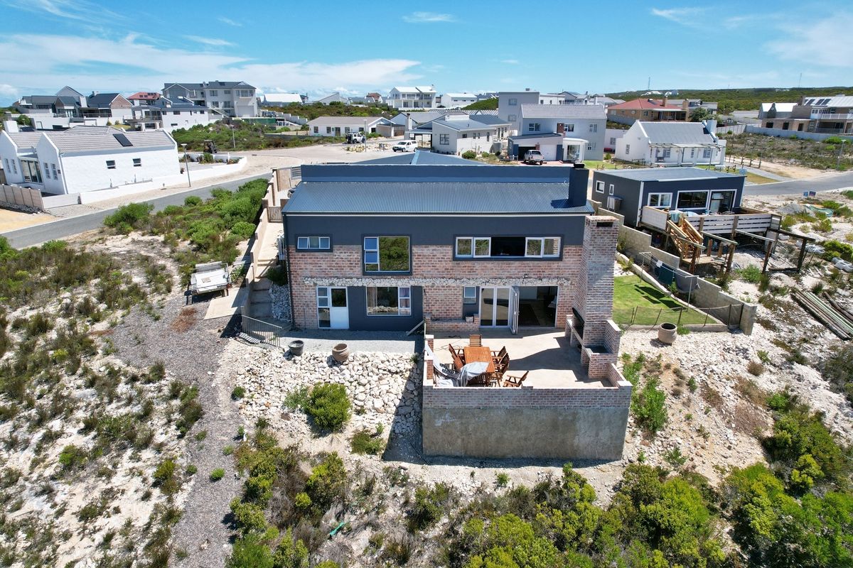 Aerial view of a modern two-story brick and metal-clad house featuring a raised patio with a built-in outdoor braai area.