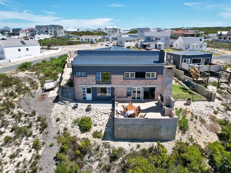 Aerial view of a modern two-story brick and metal-clad house featuring a raised patio with a built-in outdoor braai area.