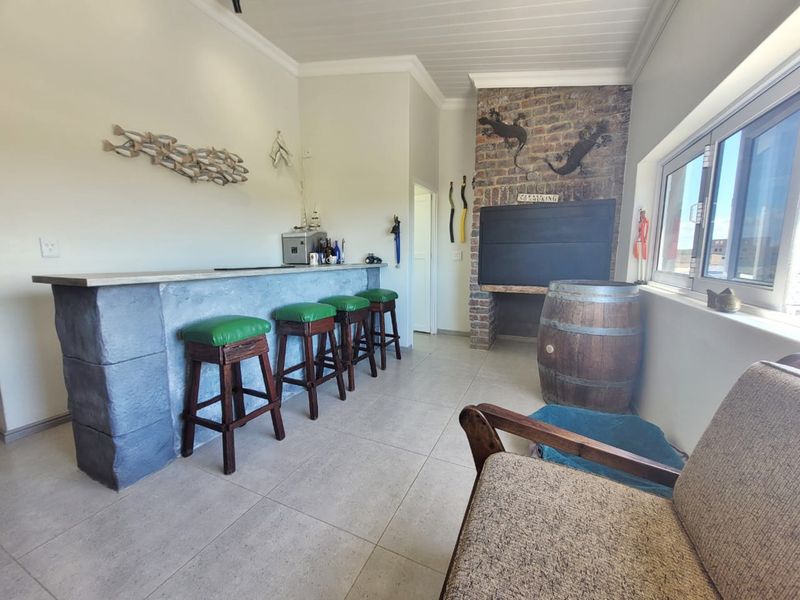 A dedicated bar area featuring a built-in counter, a rustic brick fireplace, tiled flooring, and large windows providing natural light.