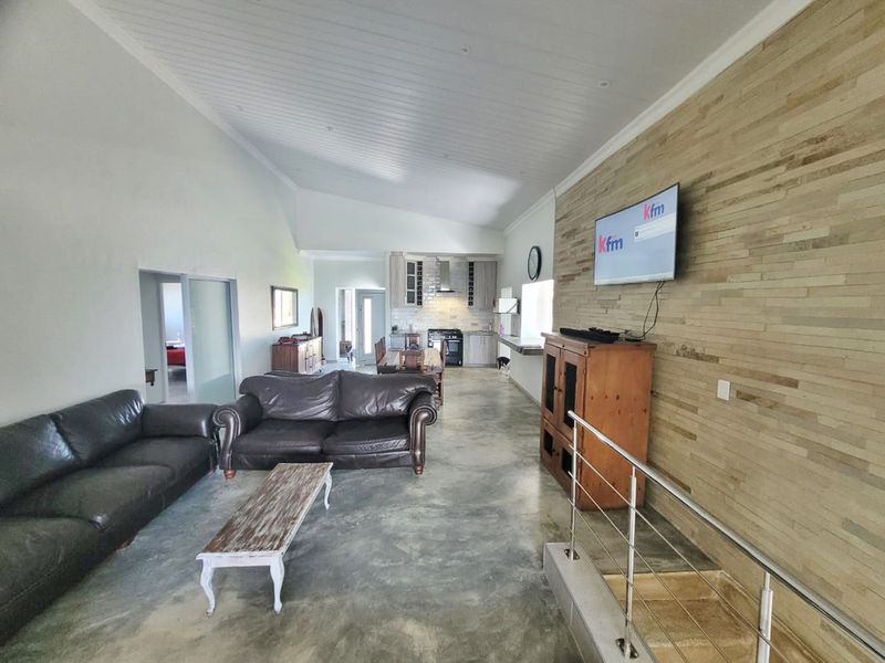 Spacious open-plan living and kitchen area featuring polished concrete floors, a vaulted ceiling, and a striking timber-clad feature wall.