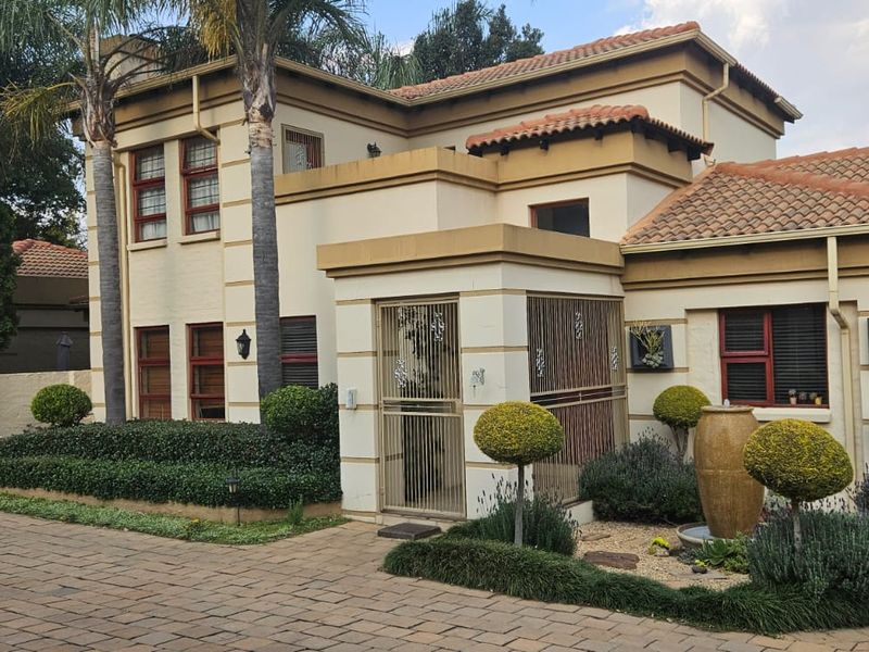 Front elevation of a two-story residential property featuring a paved driveway, security gate entrance, tiled roof, and integrated solar panels.