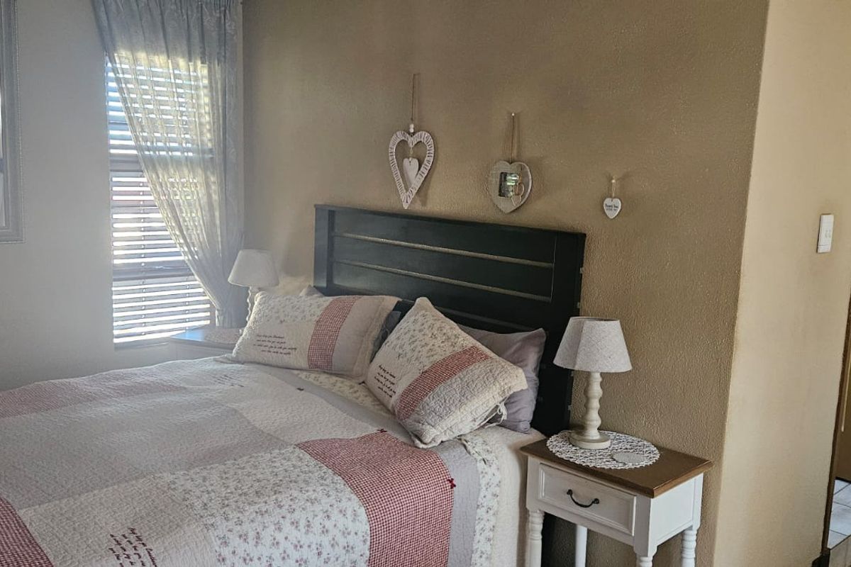A cozy bedroom featuring neutral wall tones, window blinds, and a built-in wardrobe, offering a comfortable and functional sleeping space.