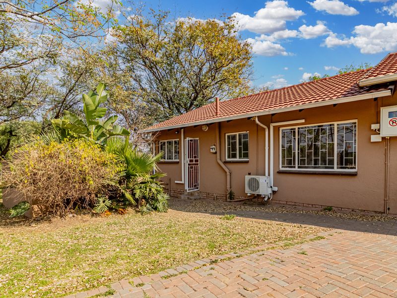Rear view of the cottage featuring a tiled roof, paved area, and established garden surroundings.