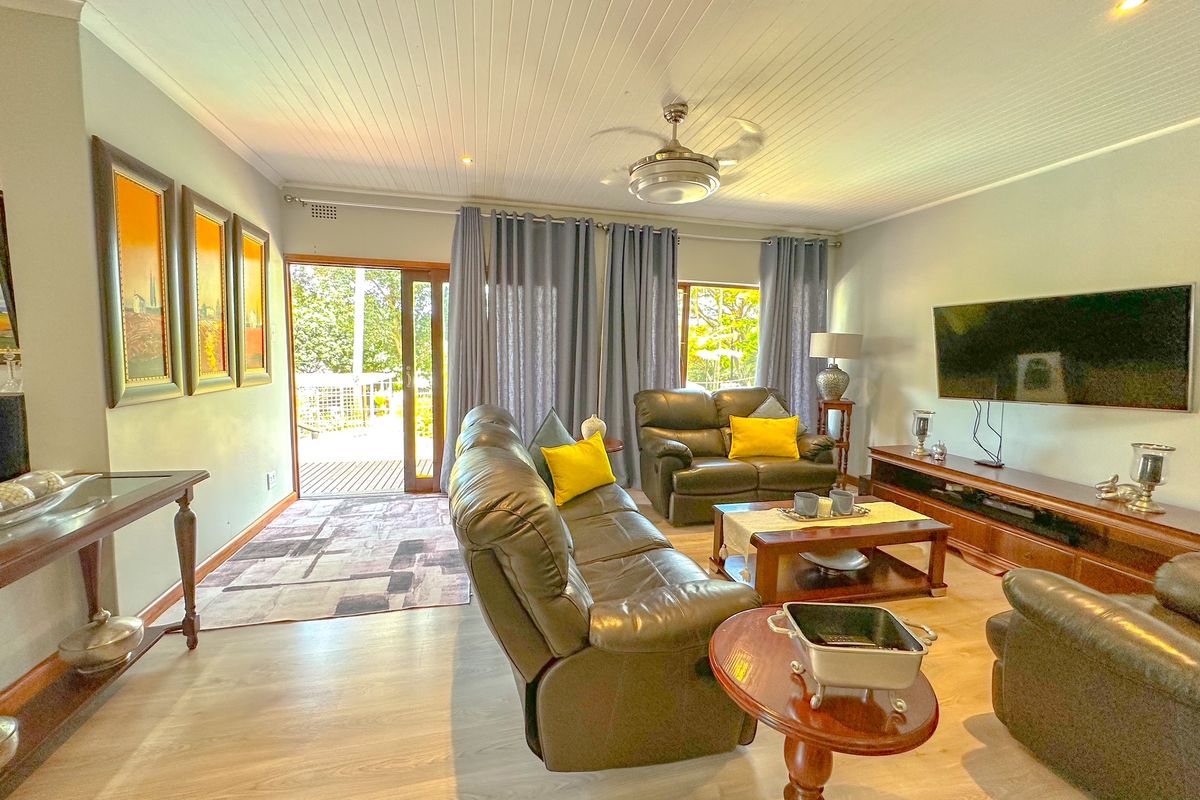Spacious living room featuring light wood-look flooring, a tongue-and-groove ceiling with a central fan, and direct access to an outdoor patio area.