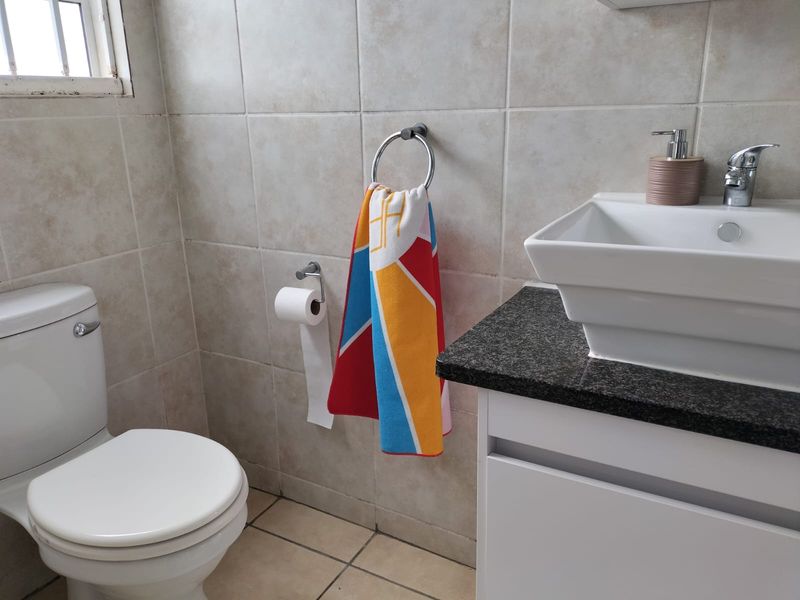 A functional bathroom featuring a modern vessel sink on a granite vanity, ceramic wall and floor tiling, and standard sanitary fixtures.