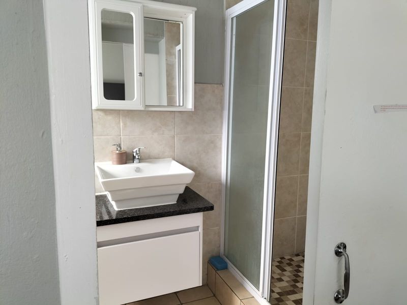 A functional bathroom featuring a vessel sink on a granite vanity, a mirrored medicine cabinet, and a separate shower enclosure with tiled finishes.