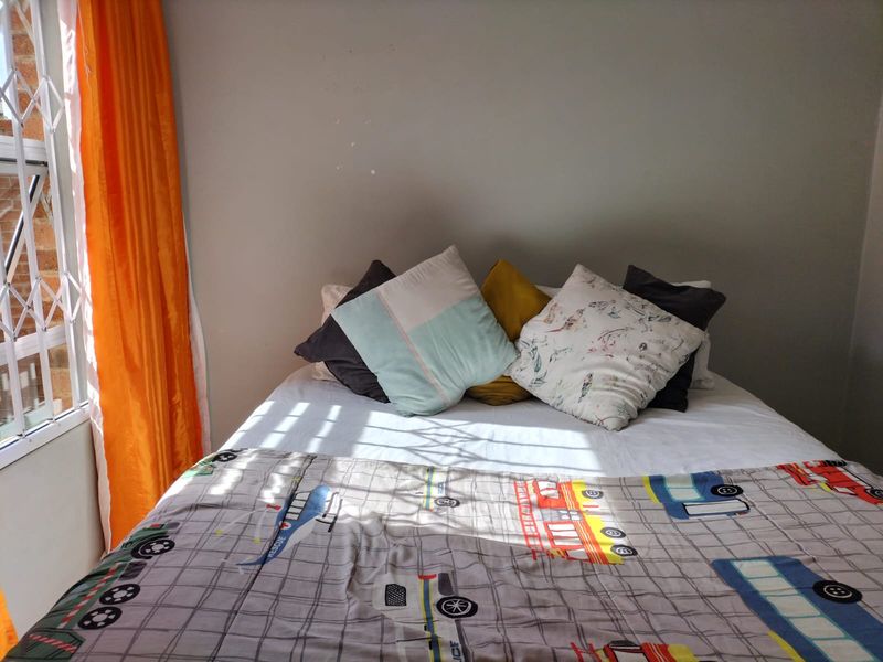 A bedroom featuring a window with a fitted security gate, providing natural light and basic security.