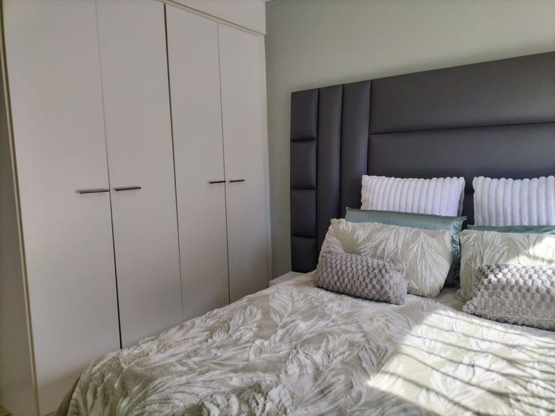A well-maintained bedroom featuring neutral walls and functional built-in cupboards with modern hardware.