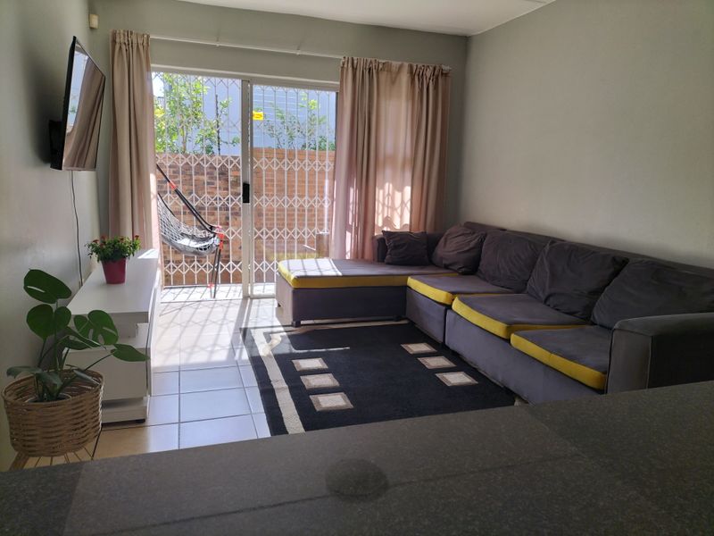 A living room featuring tiled flooring and a sliding glass door with a security gate leading to an outdoor area.