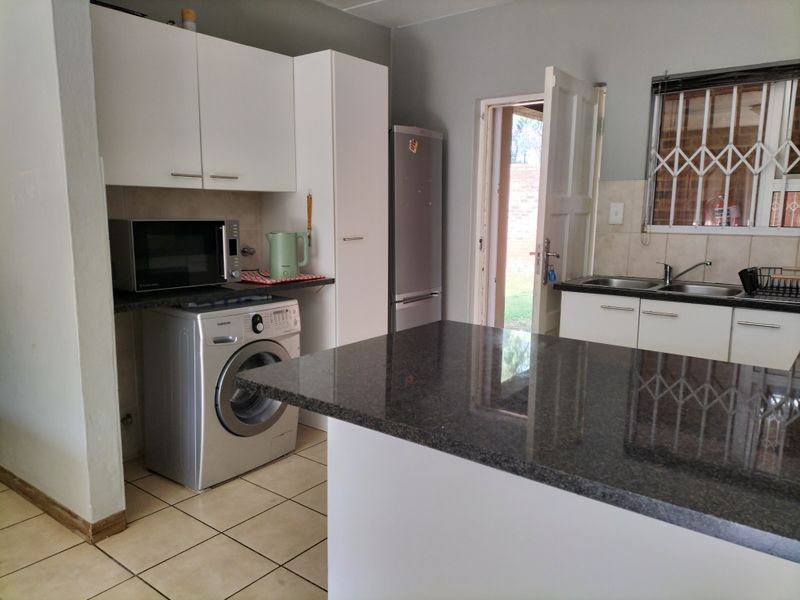 Functional kitchen featuring granite countertops, ample cabinetry, double sink, and direct access to the exterior, providing a practical layout for daily use.