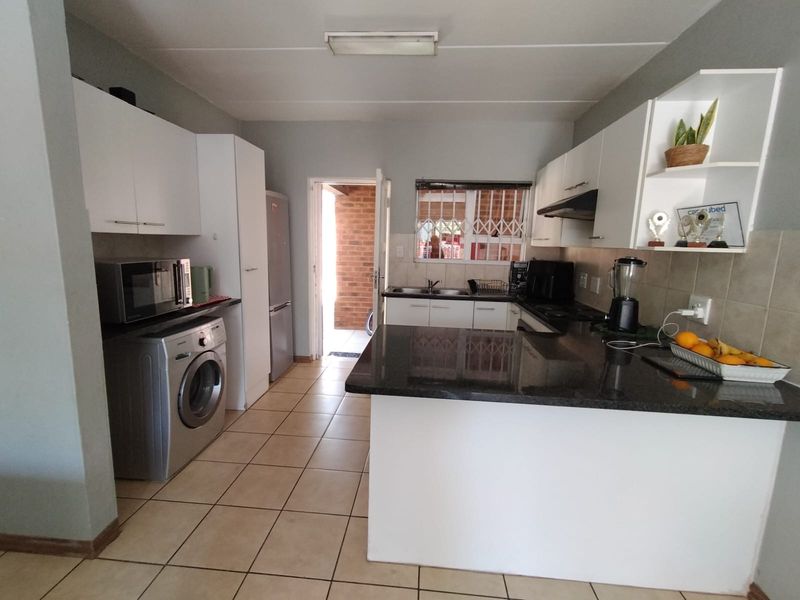 Functional kitchen featuring granite countertops, white cabinetry, tiled flooring, and direct access to an outdoor area.