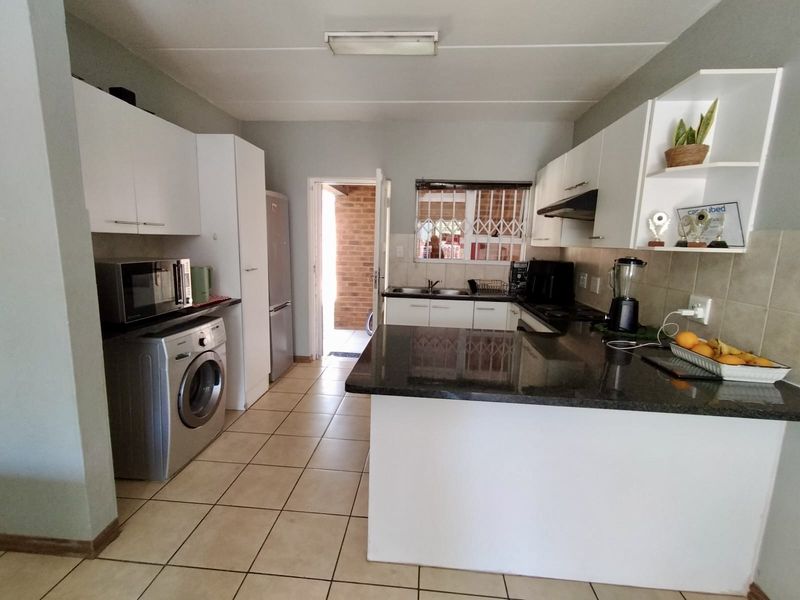 Functional kitchen featuring granite countertops, ample cabinetry, and tiled flooring, with direct access to an outdoor area.