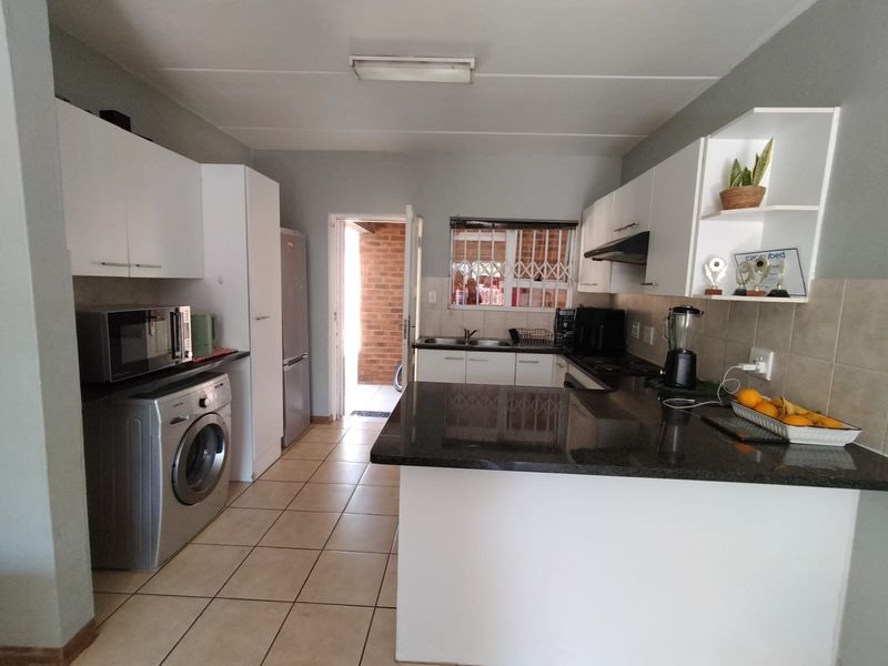 Functional kitchen featuring white cabinetry, granite countertops, tiled flooring, and direct access to an outdoor area.