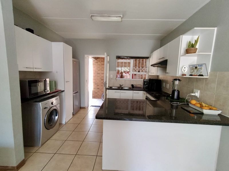 Functional kitchen featuring granite countertops, ample built-in cabinetry, tiled flooring, and a convenient layout with direct access to an outdoor area.