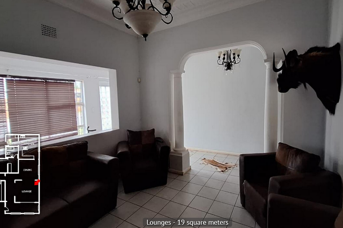 A spacious living room featuring tiled flooring, an arched entryway, and decorative ceiling light fixtures, providing a functional and open living area.