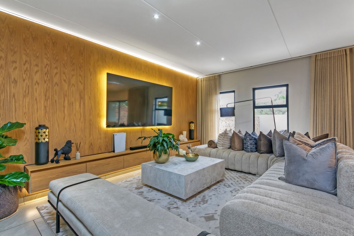 Modern living room featuring a wood veneer feature wall with integrated LED lighting, built-in floating cabinetry, and recessed downlights.