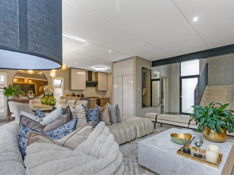 Spacious open-plan living and dining area featuring modern cabinetry, recessed lighting, and a contemporary staircase, creating a seamless flow throughout the home.