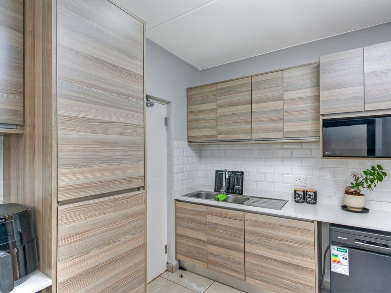 Modern kitchen featuring wood-grain cabinetry, white subway tile backsplash, integrated microwave, and durable laminate countertops.