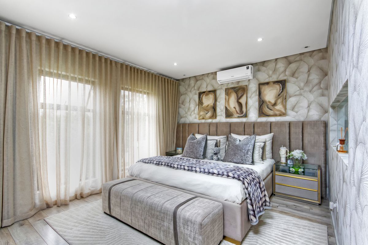 A well-appointed bedroom featuring modern recessed lighting, a wall-mounted air conditioning unit, elegant floor-to-ceiling curtains, and stylish patterned wallpaper.