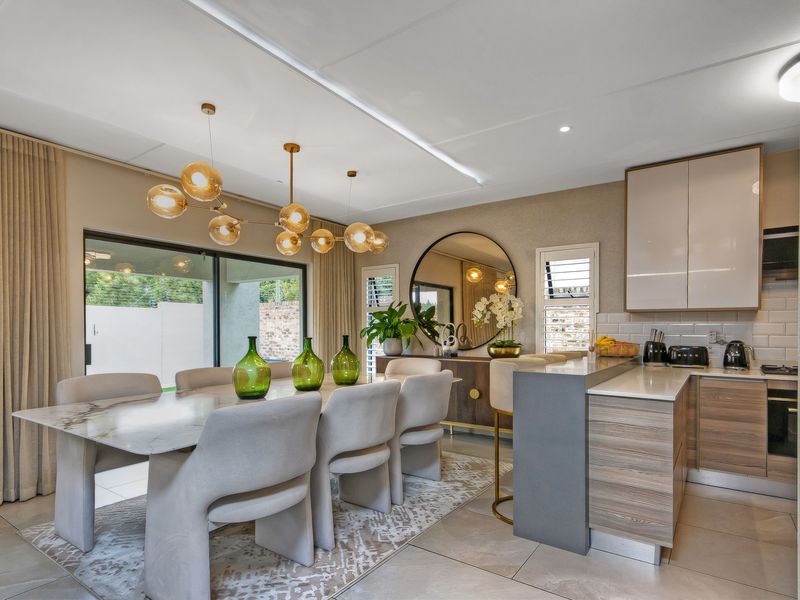 Modern open-plan kitchen and dining area featuring sleek cabinetry, stone countertops, subway tile backsplash, and large sliding doors leading to the outdoor space.