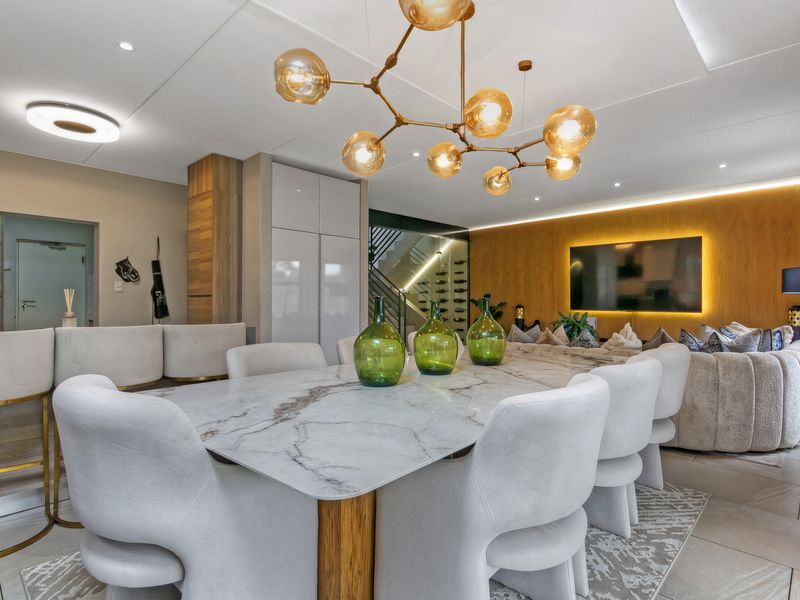 Modern open-plan living and dining area featuring high-end finishes, wood paneling, recessed lighting, and a sophisticated contemporary design.