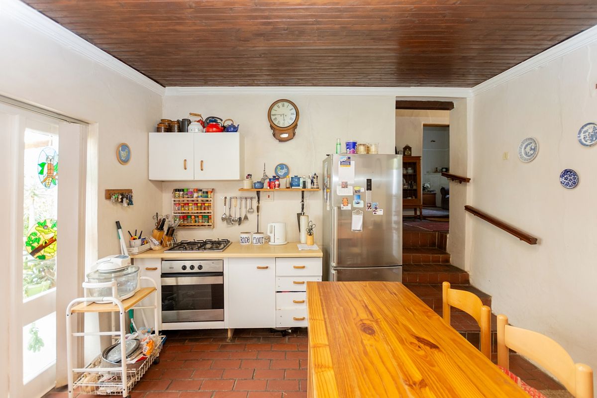 A functional kitchen featuring timber ceilings, terracotta flooring, and built-in cabinetry with an integrated oven and gas hob.