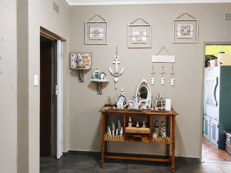 A neutral-toned hallway featuring tiled flooring and access to adjacent rooms, providing a functional transition space within the home.