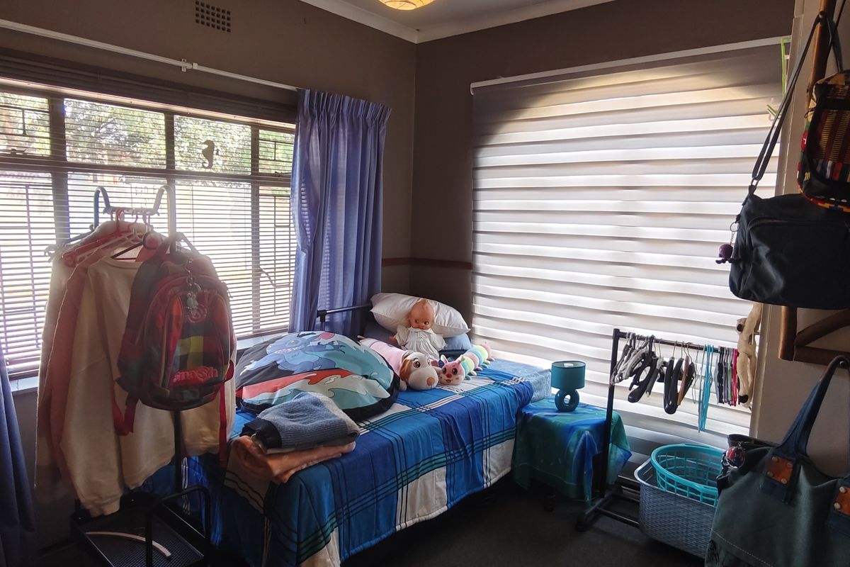 A bedroom featuring dual window treatments with horizontal blinds and curtain rails, providing natural light and privacy.